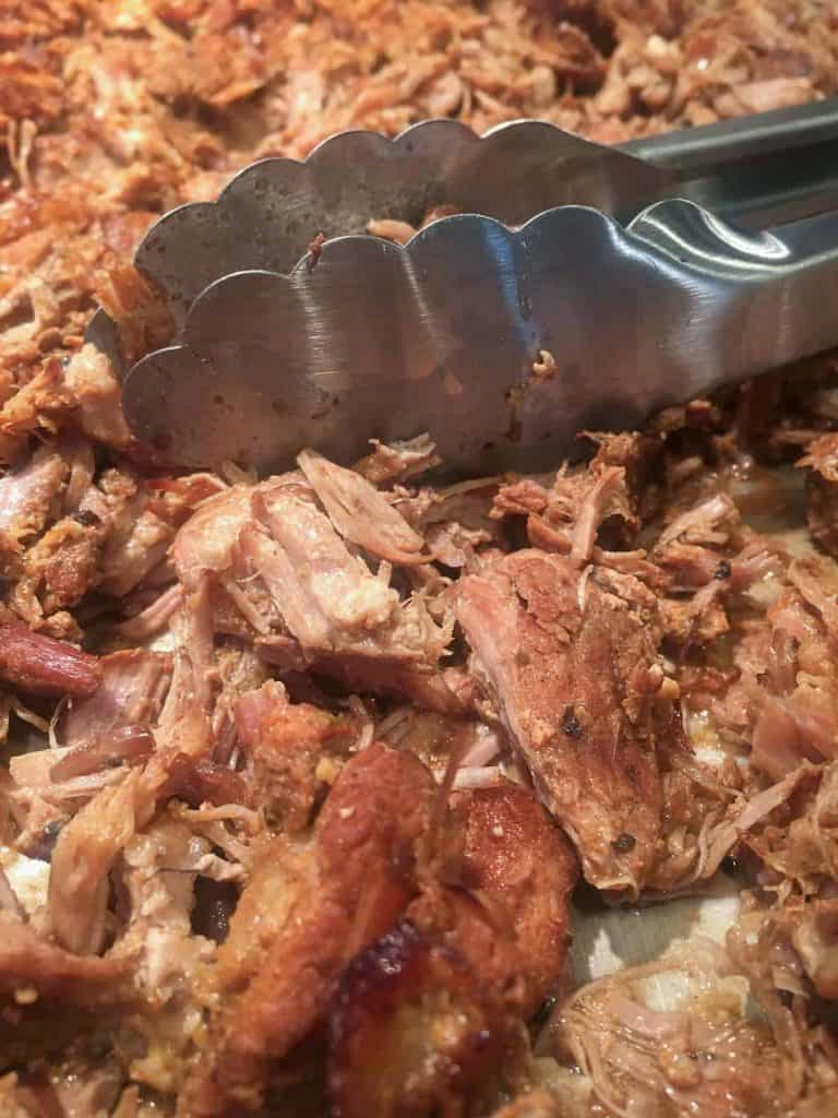pork carnitas with stainless steel tongs