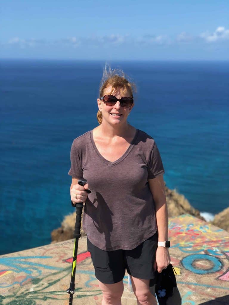 Amy with hiking stick on top of pillbox in Hawaii