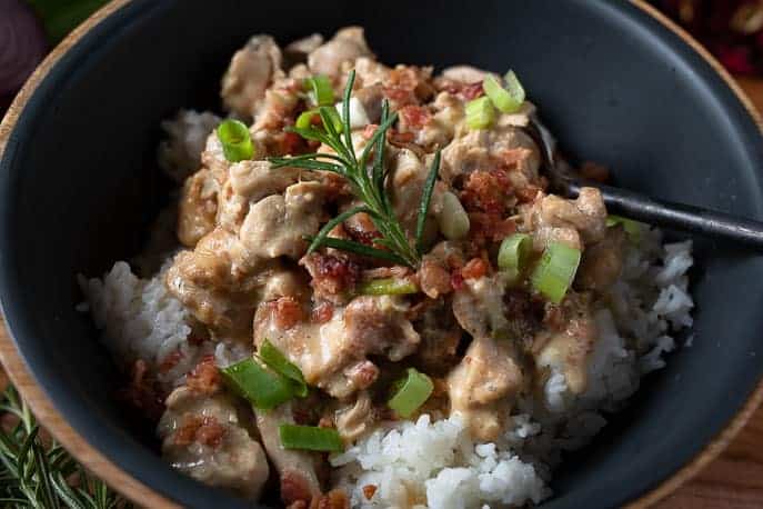 Close up of Instant Pot Gourmet Crack Chicken in a black bowl with black spoon over rice