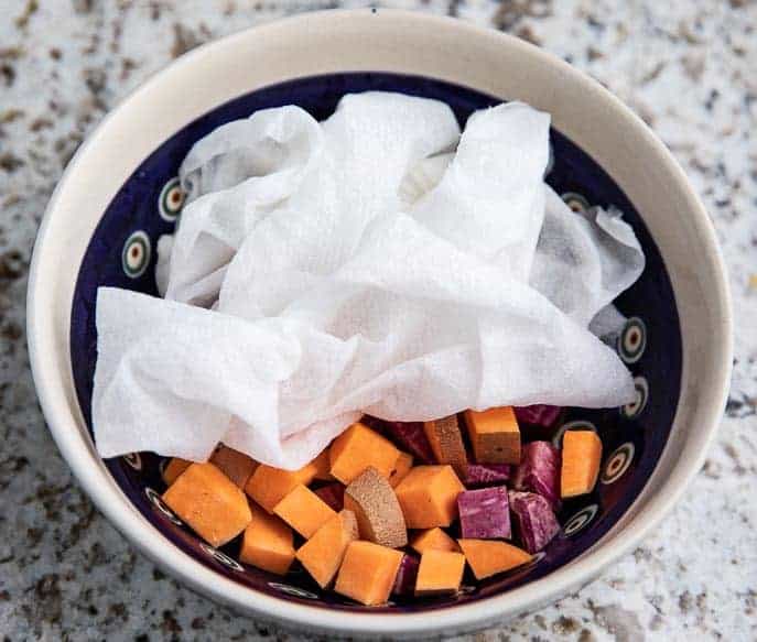 Polish pottery bowl with chopped sweet potatoes - yellow and purple with a damp paper towel over the top