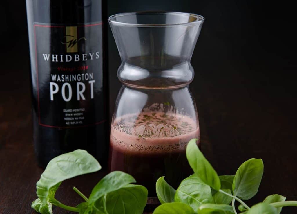 vinaigrette in glass jar with a bottle of port wine and basil leaves in the foreground