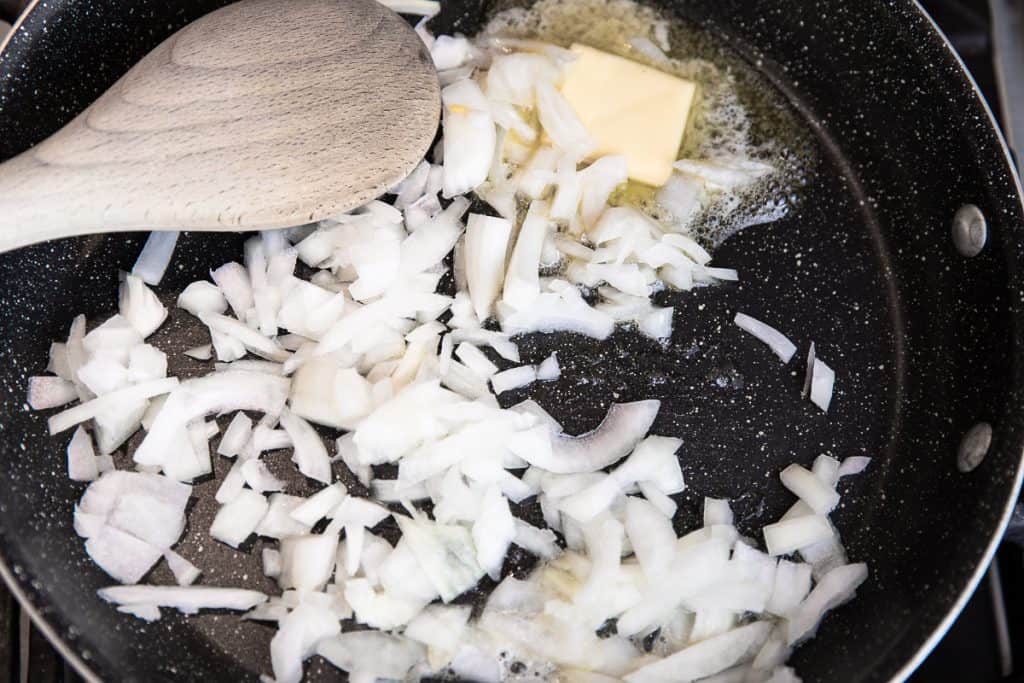 onions and butter cooking in a pan with a spoon