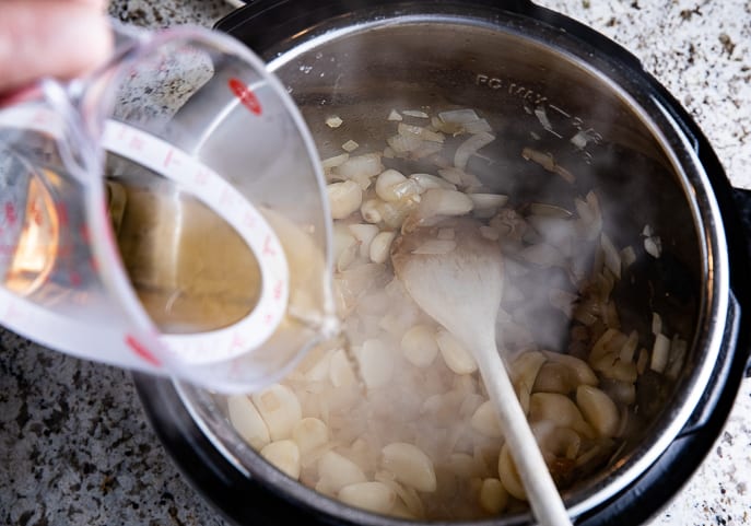 sherry and chicken broth being added to garlic onion mixture