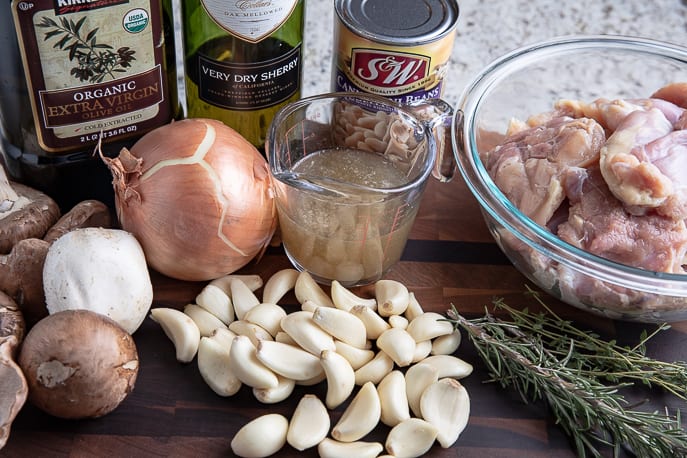 ingredients for 40 clove garlic chicken on a board - garlic, chicken, rosemary, broth, onion, mushrooms, beans, sherry